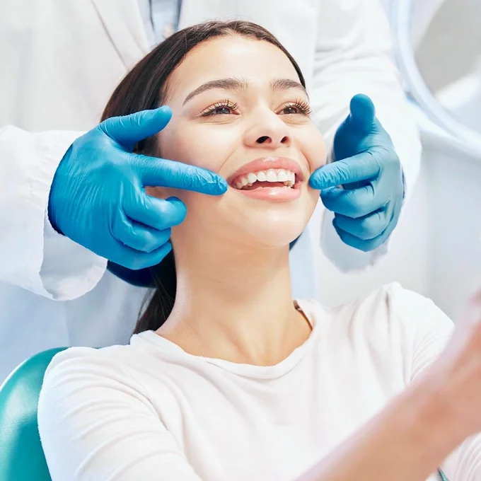 Paciente sonriendo en el sillón dental mientras el odontólogo revisa su sonrisa